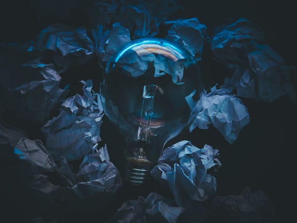 Home A light bulb surrounded by crumpled paper symbolizes creative ideas and innovation in a dark setting.